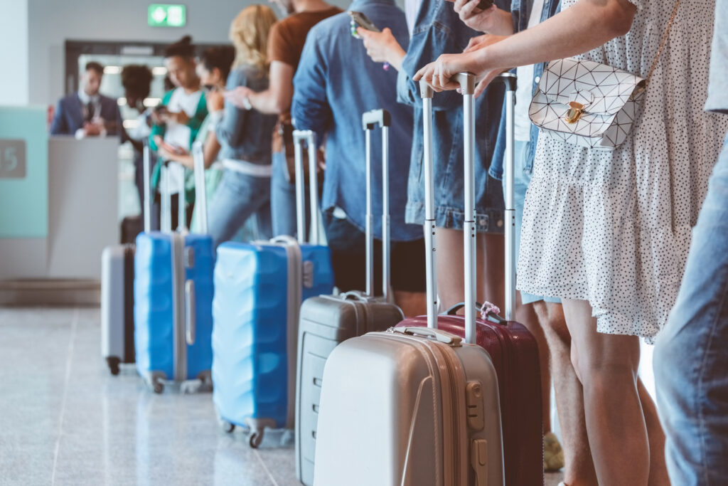 Passagiere stehen Schlange am Flughafengate aufgrund einer Überbuchung.